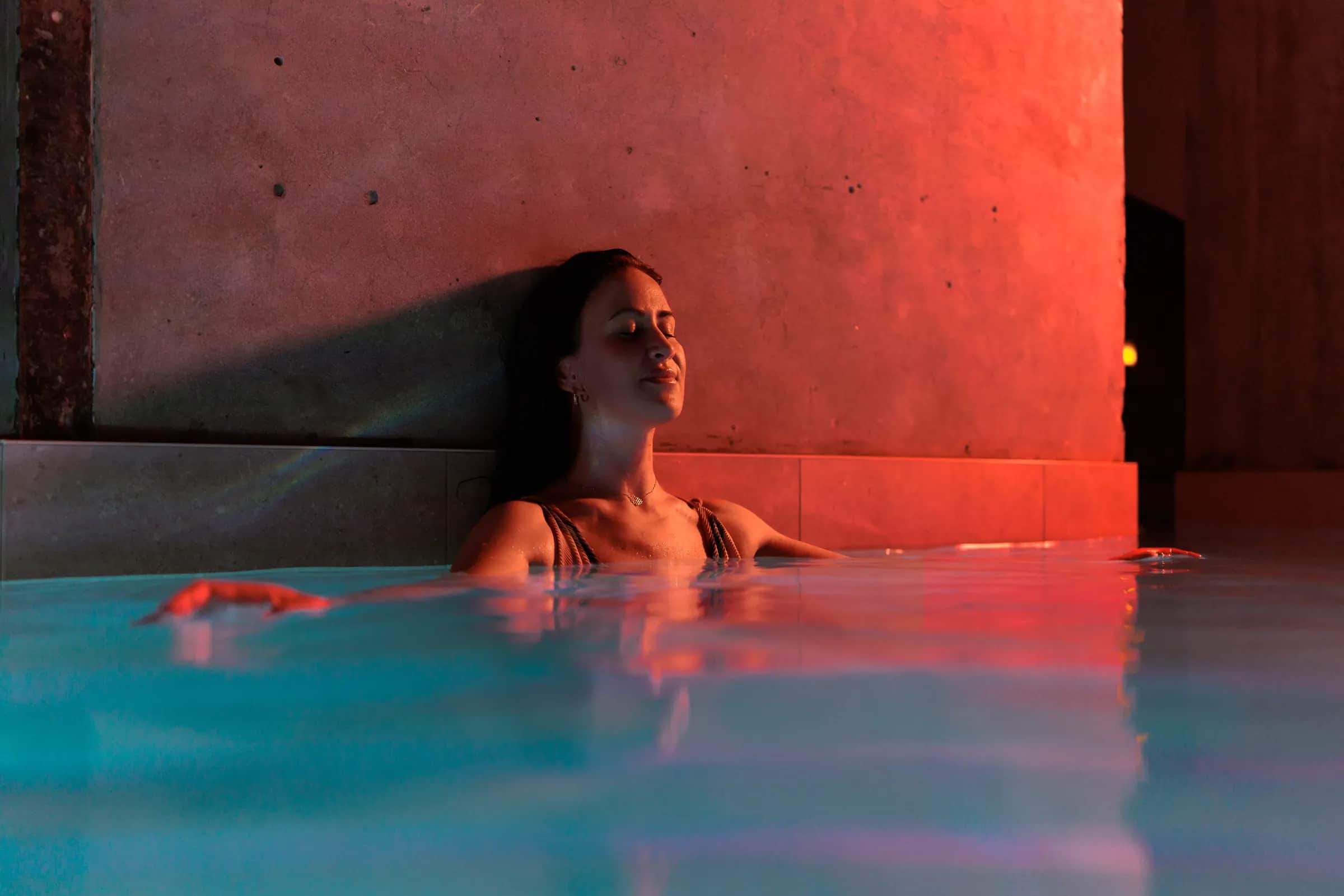 Joy Wellness — the red-lit pool, a guest at rest
